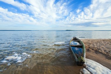 Old flooding boat on summer lake shore clipart