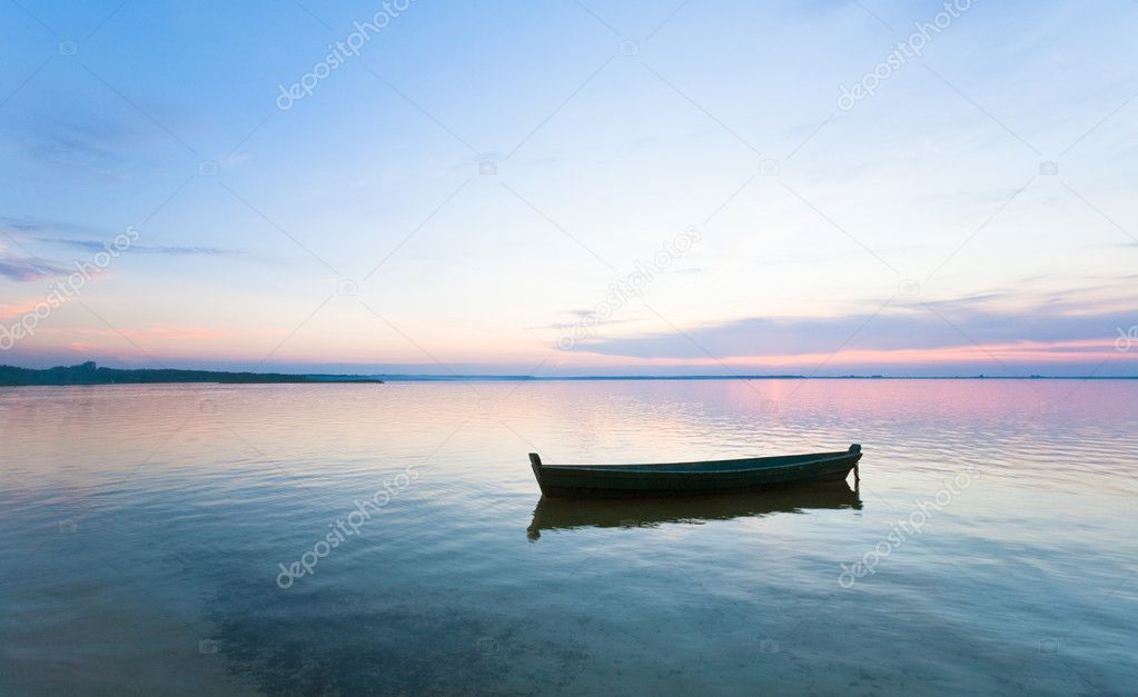 Sunset and boat on summer lake bank
