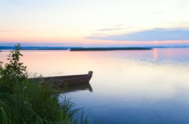 Sunset with boat near the summer lake shore clipart