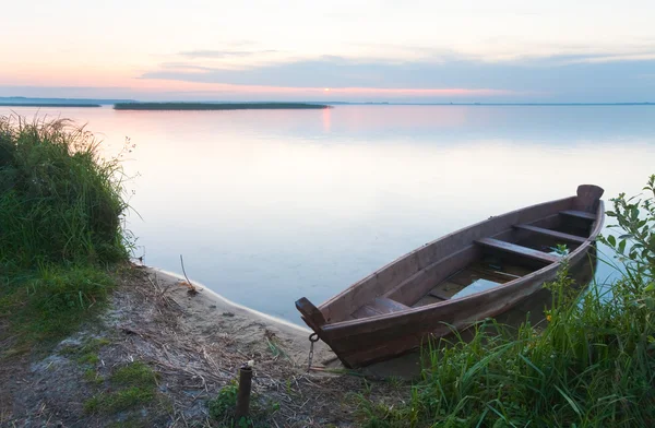 Sunset with old flooding boat on summer lake shore — Stock Photo, Image