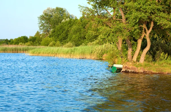 Лодка возле летнего берега озера — стоковое фото