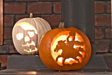 Halloween carved pumkins sitting on the wood stove clipart