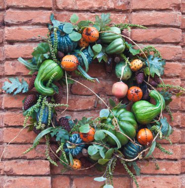 Brick wall decorated for autumn with gords in a wreath, in california mid december clipart