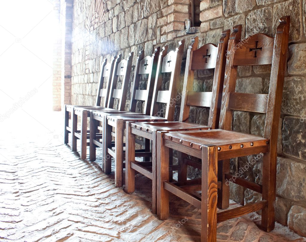 A row of chair lined up against the wall tith religios simbols on them and a bright back light