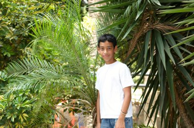 tropik bitkiler arka planda gülümseyen bir çocuk portresi.