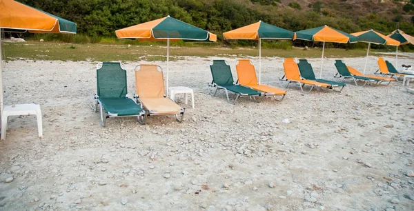 Cadeiras lounge de praia sob sombra de guarda-chuvas  . — Fotografia de Stock