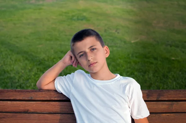 Boy Sitting Park Bench Green Meadow Background — Stock Photo, Image