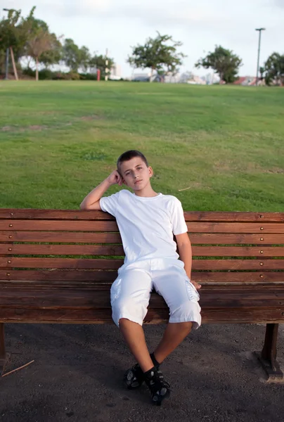 Junge Sitzt Auf Einer Parkbank Mit Grüner Wiese Hintergrund — Stockfoto
