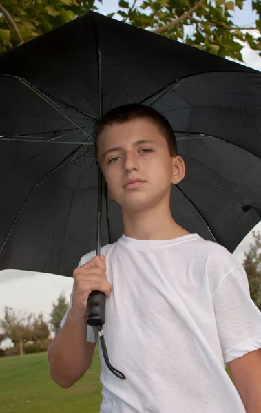 Junge Schaut Kamera Während Draußen Unter Regenschirm Sitzt — Stockfoto