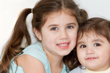 Cute Hispanic-American sisters pose and smile for a portrait. clipart