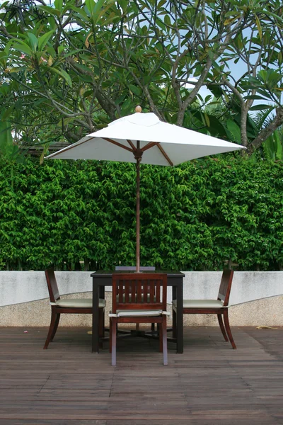 Стул, стол и белый зонтик в саду — стоковое фото