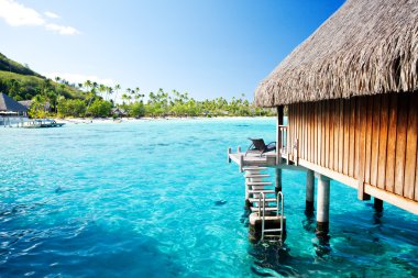 Over water bungalow with steps into amazing lagoon clipart