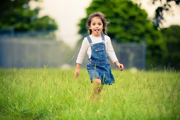 Glückliches Mädchen, das auf einer grünen Wiese spaziert — Stockfoto