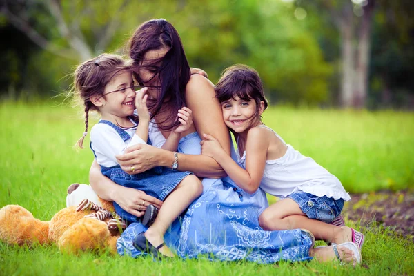 Mor och två döttrar leker i gräset — Stockfoto