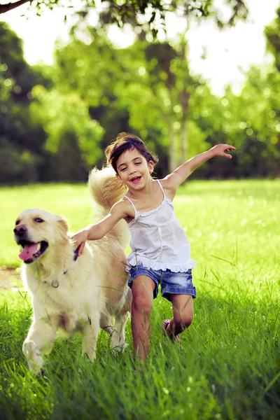 Młoda dziewczyna z złoty pies myśliwski działa — Zdjęcie stockowe