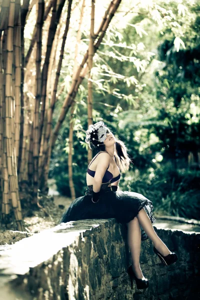 브래지어와 대나무 아래에 앉아 발뒤꿈치에 여자 — 스톡 사진