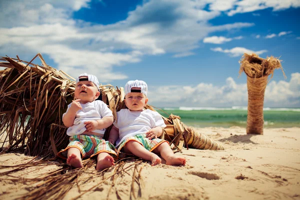 Identiska tvillingpojkar avkopplande på en strand — Stockfoto