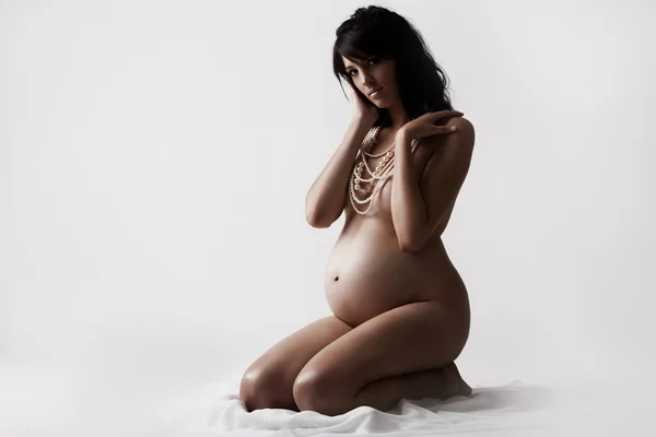Молодая обнаженная беременная женщина сидит на земле — стоковое фото