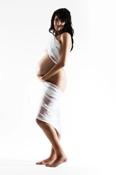 Молодая беременная женщина, завернутая в белую ткань — стоковое фото