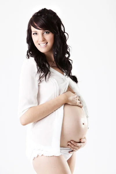 Молодая беременная улыбающаяся женщина в белой рубашке — стоковое фото