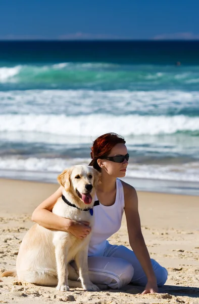 Mladá žena sedí na pláži se psem — Stock fotografie
