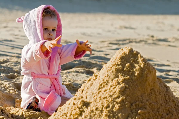 Kind bereiken voor een zand op het strand — Stockfoto
