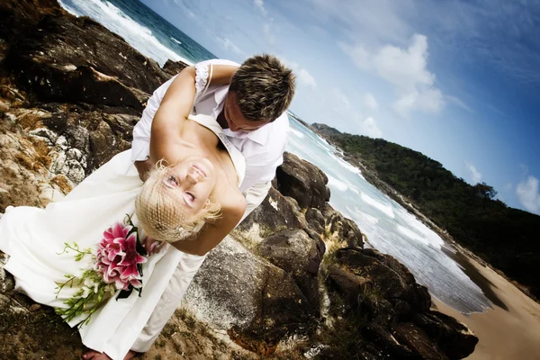 充满激情的年轻夫妇结婚了上海滩站在岩石上 — 图库照片