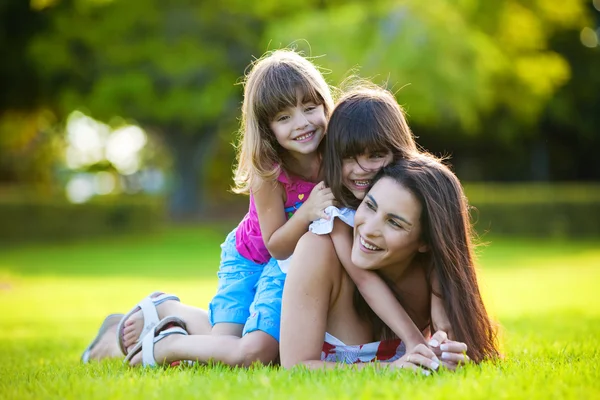 若い母親と 人の娘が草で遊ぶ — ストック写真