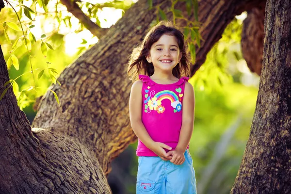Uśmiechnięta młoda dziewczyna stoi na gałęzi drzewa — Zdjęcie stockowe