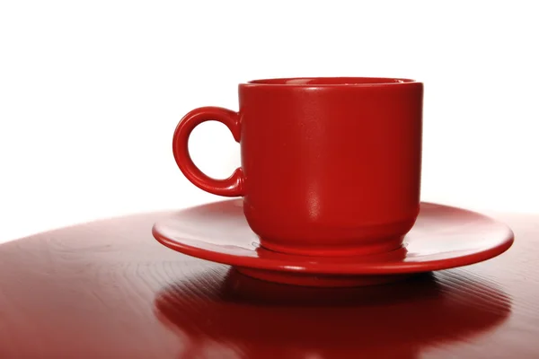 赤いテーブル上の受け皿と赤のカップ — ストック写真