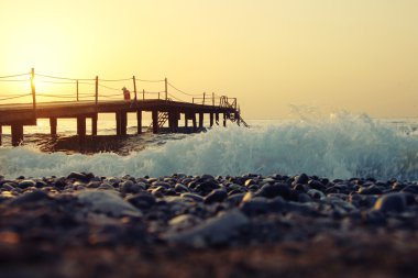 İskele, pebles ve dalgalar deniz güzel gündoğumu