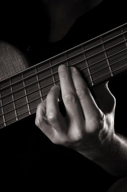 Playing six-string electric bass guitar; fretting left hand; toned monochrome image; clipart