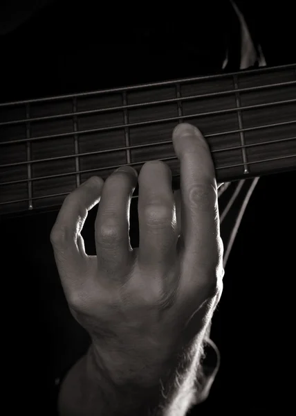 Playing six-string electric bass guitar; fretting left hand; toned monochro — Stock Photo, Image