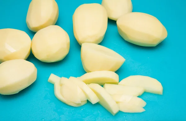 Elaboración de papas fritas - pelar y cortar parcialmente las papas en plástico azul c —  Fotos de Stock