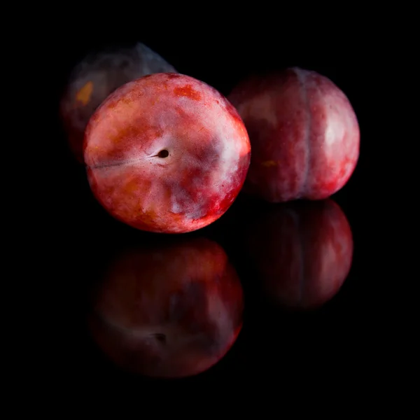 Reife rote und violette Pflaumenfrüchte; isoliert auf schwarzem Hintergrund mit Reflektoren — Stockfoto