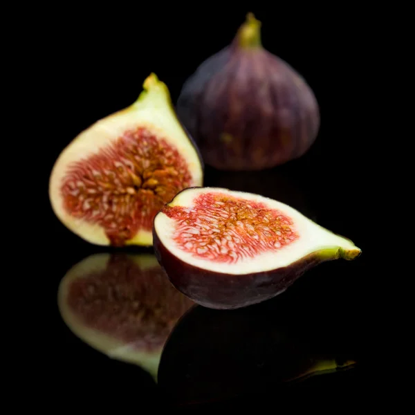 Frutti di fico viola maturi isolati su fondo nero, con riflesso — Foto Stock