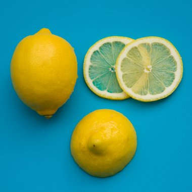 Kesme limon - bütün limon; yarısı; ve dilimleri parlak mavi plastik kesme tahtası