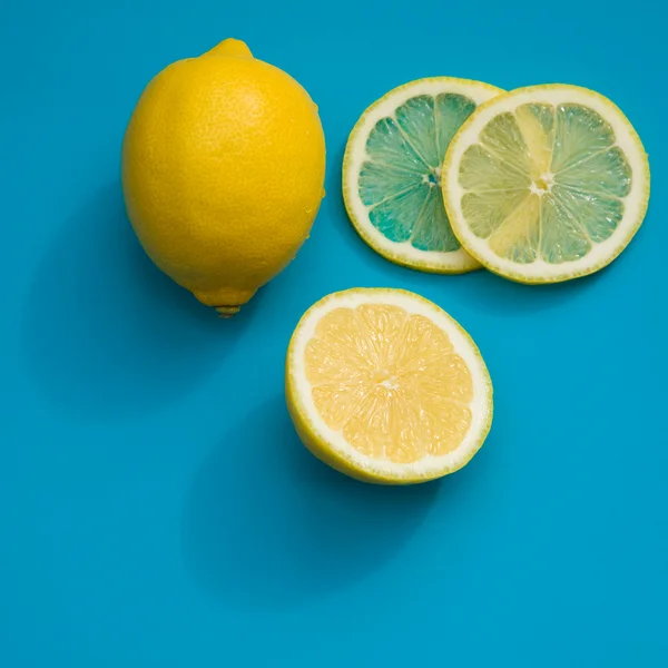 Cutting lemon - whole lemon; half; and slices on bright blue plastic cuttin