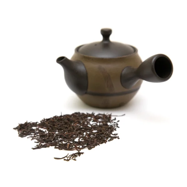 Pequeña tetera de cerámica individual y hojas de té dispersas en whit —  Fotos de Stock