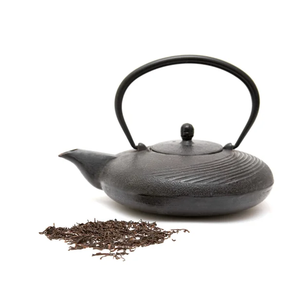 Gusseiserne Schwarze Teekanne Und Verstreute Trockene Teeblätter Auf Weißem Hintergrund — Stockfoto