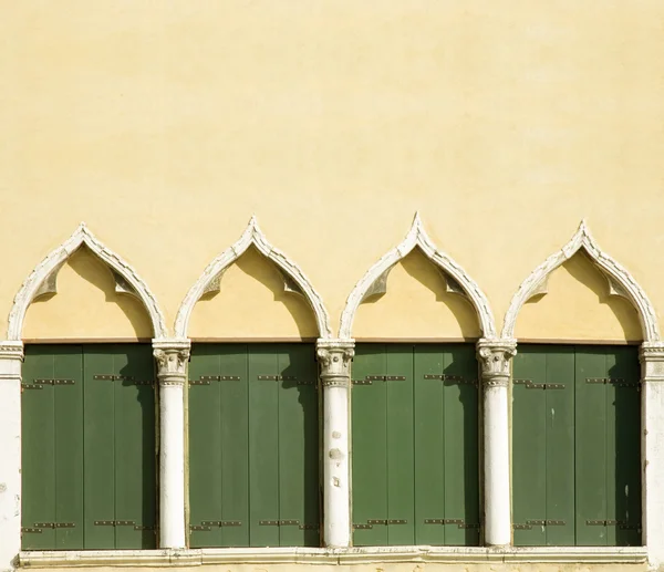 Architecturale achtergrond - gewelfde ramen met groene houten luiken — Stockfoto