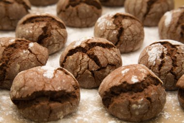 Tray of freshly made chocolate cookies with icing sugar dusting clipart