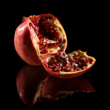 Pomegranate; broken fruit isolated on black reflective surface; clipart