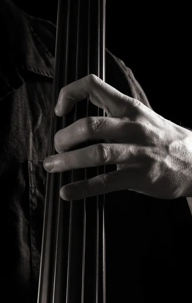 Чоловіча рука на шиї електричного подвійного баса; тонове монохромне зображення — стокове фото