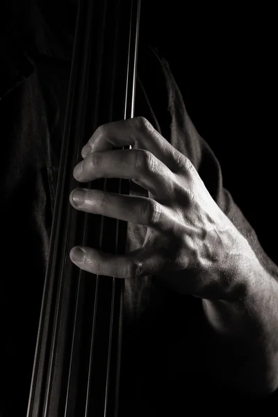 Чоловіча рука на дошці електричного подвійного баса; тоноване монохромне зображення — стокове фото