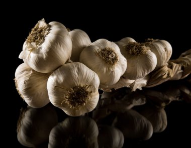 Plait of garlic bulbs close-up isolated on black background with reflection clipart