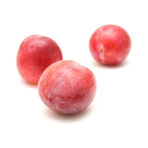 Ciruelas grandes maduras de color rojo claro, tres frutas, aisladas sobre fondo blanco — Foto de Stock