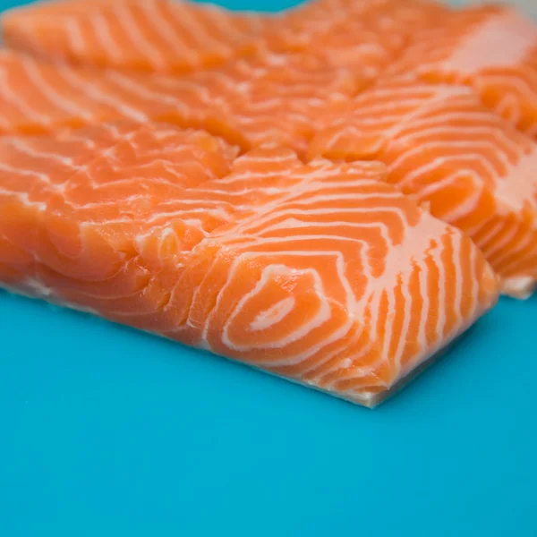 Raw fresh trout portions on blue plastic chopping board; — Stock Photo, Image