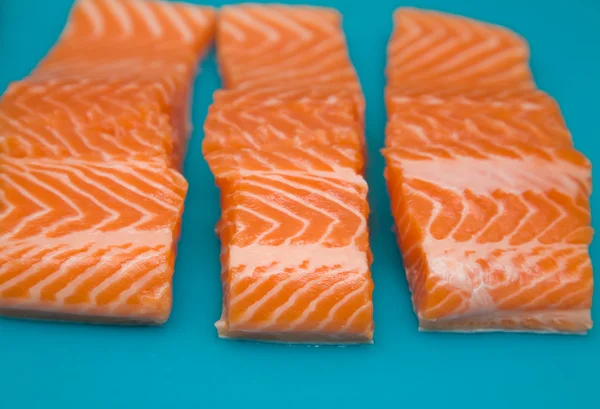 Raw fresh trout portions on blue plastic chopping board; — Stock Photo, Image