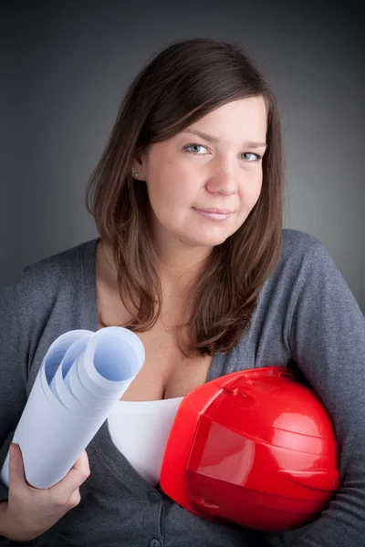Portrait of young architect wearing red hardhat, looking at came — Stock Photo, Image